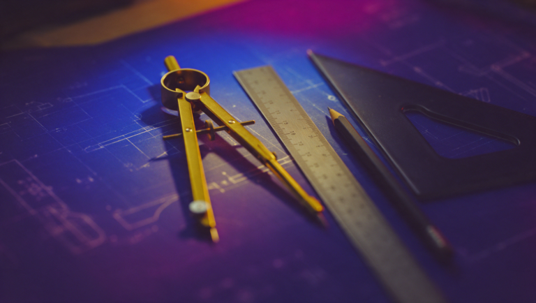 Drafting compass, ruler and set square laid on a blueprint